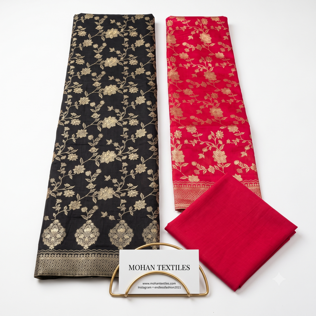 Flat lay of Black & Pink unstitched Banarasi style party wear dress material, featuring intricate gold zari floral weaving and a matching dupatta, available at Mohan Textiles.