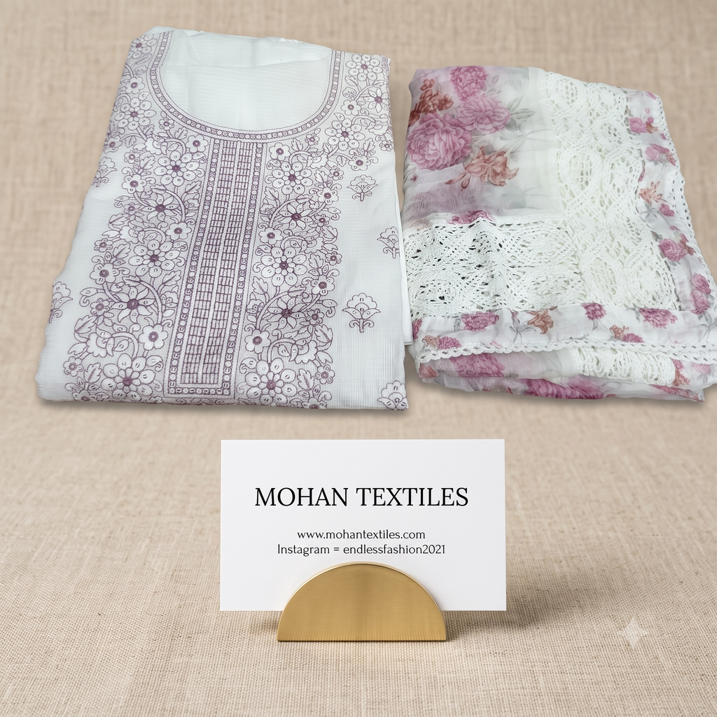 A folded white traditional embroidered kurta set from Mohan Textiles, featuring a white kurta with purple floral embroidery on the left and a matching white lace and floral dupatta on the right, displayed on a beige textured fabric background with a brand card.